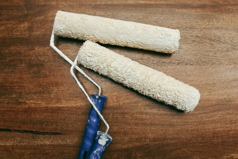 木质台面上的涂料滚筒与漆料，漆液匀开